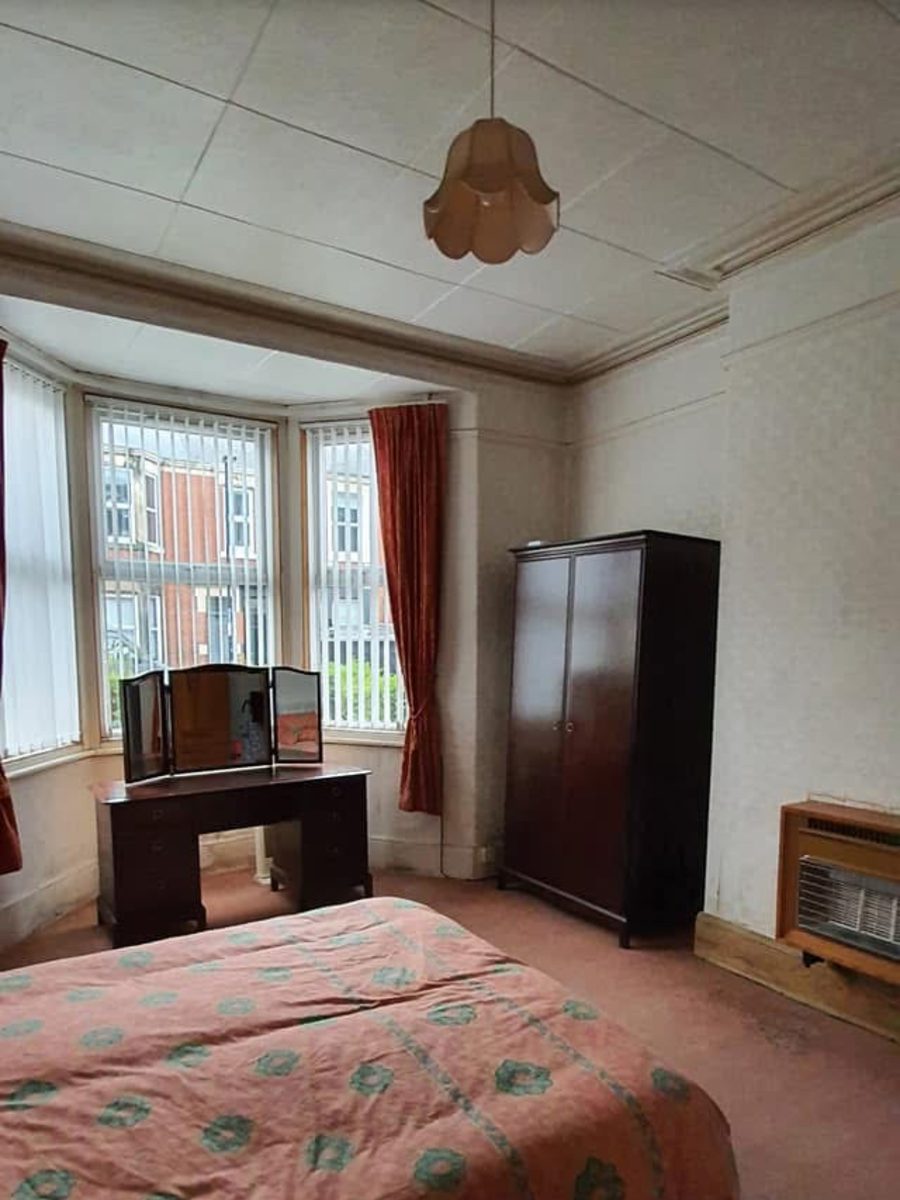 Dated bedroom with old carpet, wallpaper and gas fire before renovation